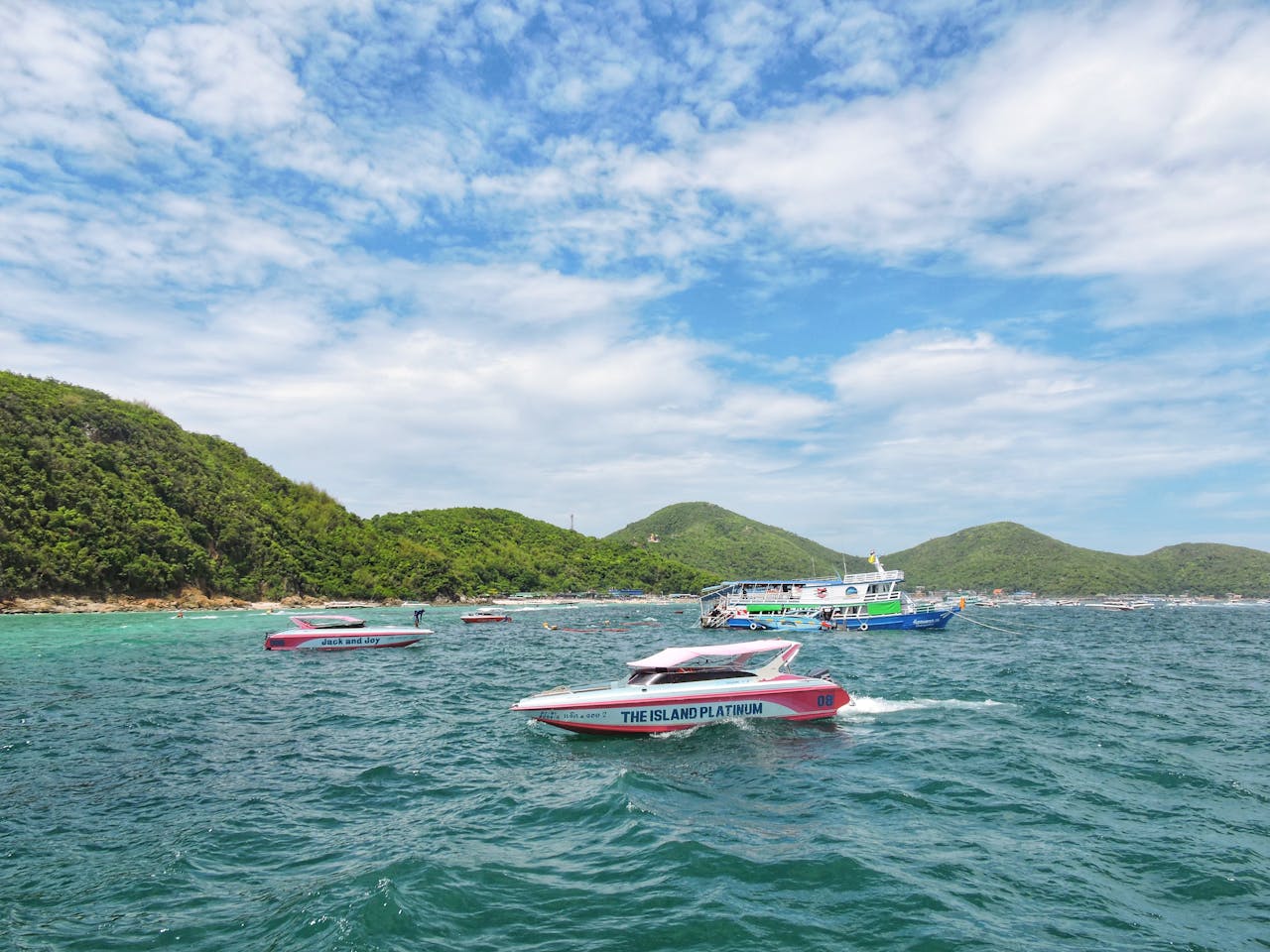 digital Colorful speedboats cruising near Ko Lan Island with lush hills and clear skies in Thailand.